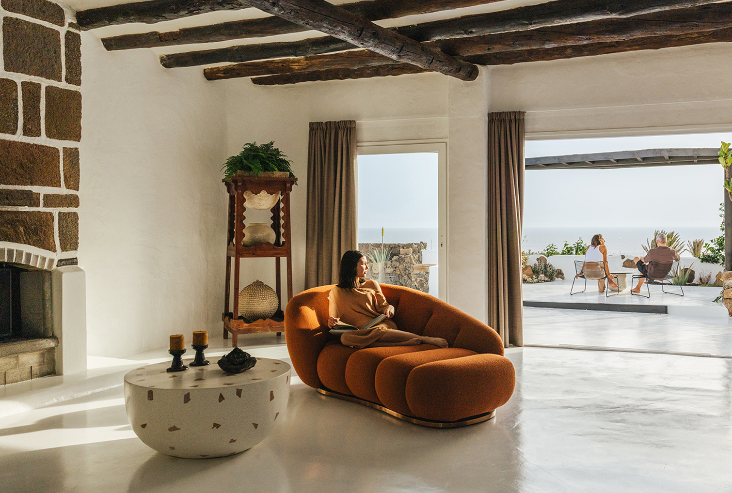 Chica relajándose y leyendo en el lobby del hotel rural Ca’Mur en Lanzarote, con sofá cómodo y vistas al mar, experiencia de turismo sostenible